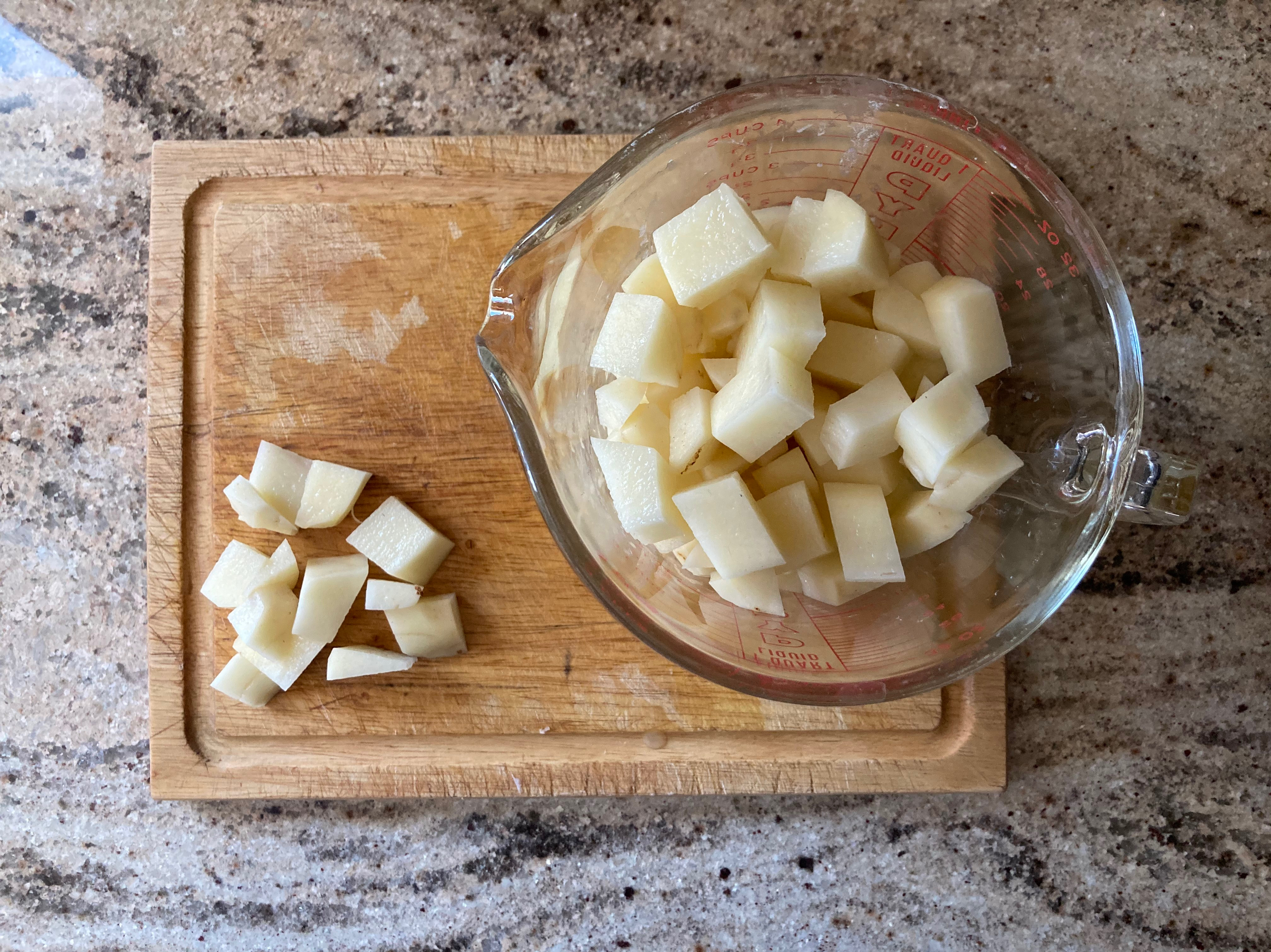 chopped potatoes on a cutting board and in a glass measuring jug