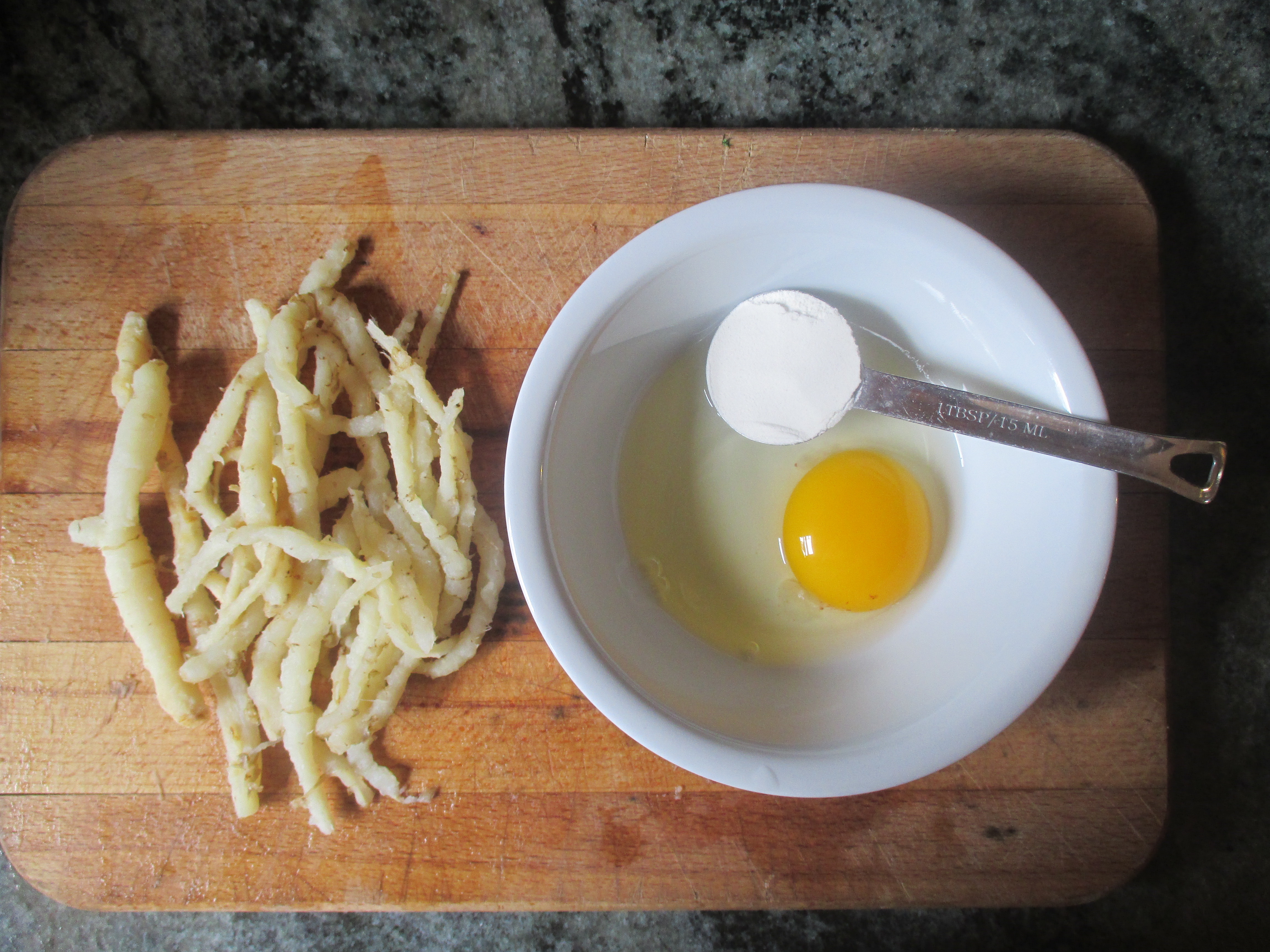 cooked and peeled skirret, egg and flour on cutting board
