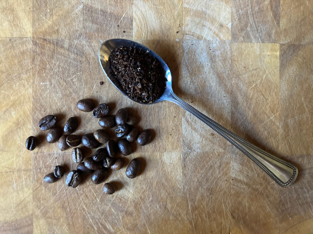 coffee beans on cutting board, coffee grounds in teaspoon