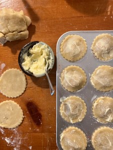 closed strawberry tarts with flavored butter and sugar on the lids, bowl of flavored butter on the side and additional dough lids