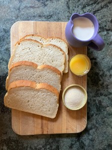 ingredients: bread on cutting board, sugar, orange juice, and cream in containers