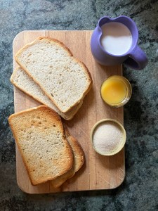 ingredients: bread on cutting board, sugar, orange juice, and cream in containers