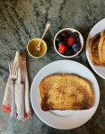finished French toast on plates, utensils, bowls with honey and berries