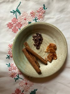 cloth background, plate with spices (mace, cinnamon) and cocoa nibs