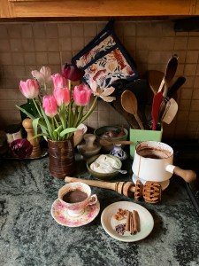 countertop with hot chocolate, flowers, cooking implements