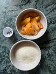 peach slices in a white bowl, sugar in a white bowl, three cloves in a white bowl
