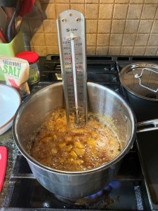 peaches and sugar syrup in a saucepan with a candy thermometer