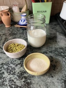 milk and cream in jar, ground pistachios in blow, sugar in bowl