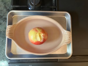 apple stuffed with butter and saffron in baking dish surrounded by water on baking sheet on stovetop