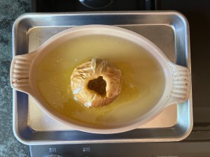 baked apple in baking dish with water on baking sheet on stove top